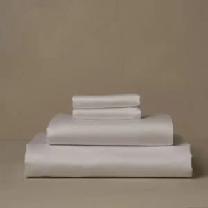 LETTO Giza Reserve Sateen sheet set folded in ivory against a warm taupe background.