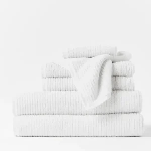Coyuchi Temescal Ribbed 6-piece towel set in white, stacked with draped washcloth.